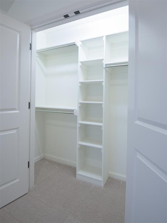 walk in closet featuring light colored carpet