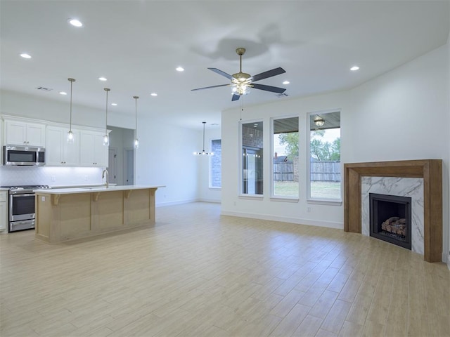 12129 SW 45th Ter, Mustang, OK 73064 - unfurnished living room with a high end fireplace, light wood-style flooring, recessed lighting, a sink, and a ceiling fan