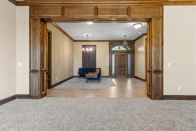 carpeted entrance foyer with ornamental molding and an inviting chandelier