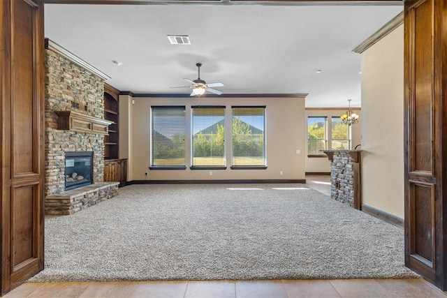 unfurnished living room featuring a fireplace, ceiling fan with notable chandelier, light colored carpet, and crown molding