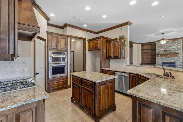 kitchen featuring a center island, stainless steel appliances, light stone counters, and sink