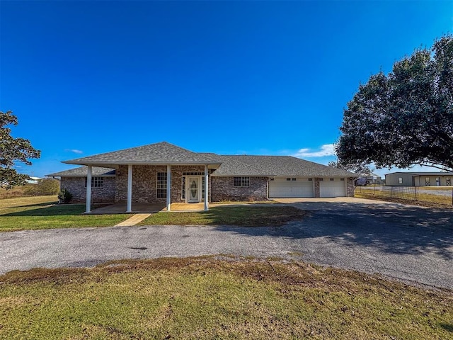 ranch-style home with covered porch, a front yard, and a garage