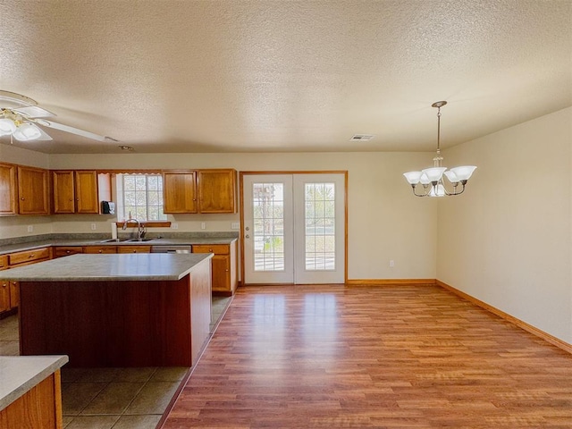 kitchen with a textured ceiling, light wood-type flooring, decorative light fixtures, and a healthy amount of sunlight