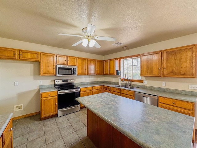 kitchen with ceiling fan, sink, stainless steel appliances, and a textured ceiling