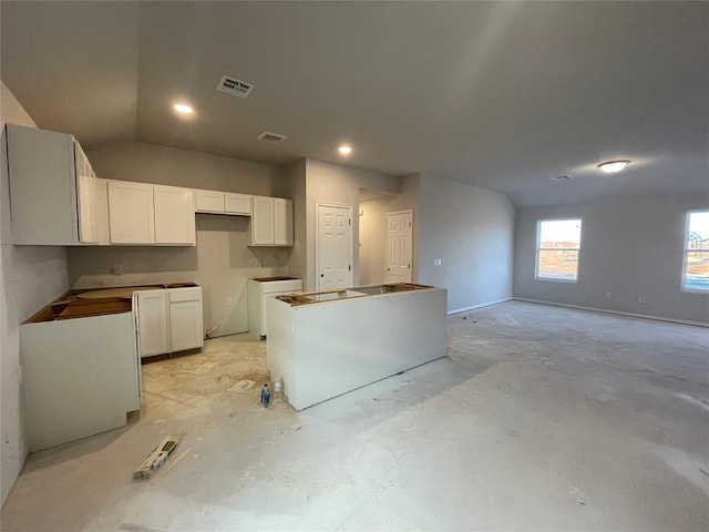 kitchen with lofted ceiling, a kitchen island, and white cabinetry