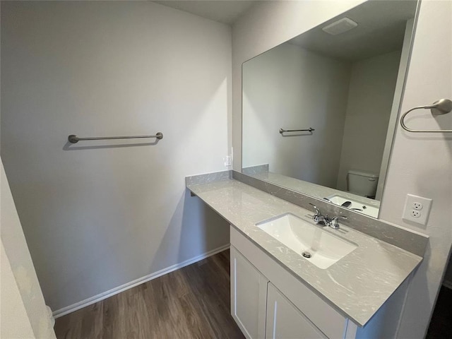 bathroom with vanity, toilet, and hardwood / wood-style floors