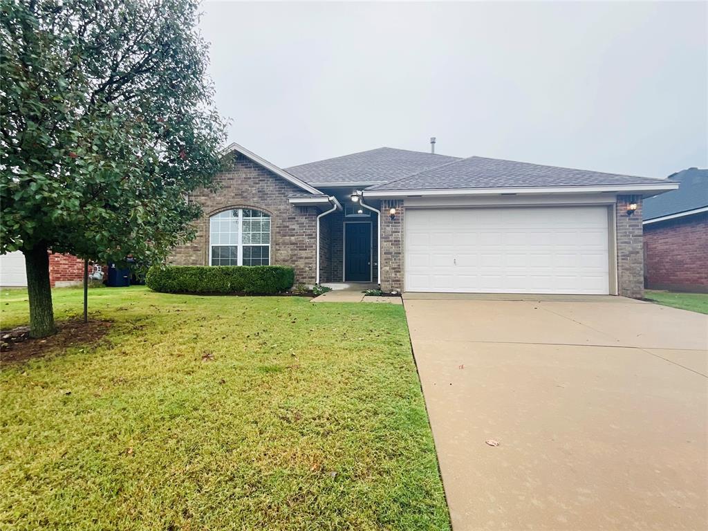 ranch-style home featuring a garage and a front lawn