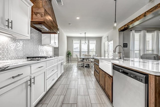 kitchen featuring a kitchen island with sink, white cabinetry, stainless steel appliances, and decorative light fixtures