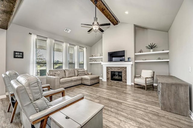 living room featuring ceiling fan, beam ceiling, high vaulted ceiling, light hardwood / wood-style flooring, and a fireplace