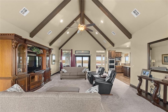 carpeted living room with beam ceiling, plenty of natural light, and high vaulted ceiling