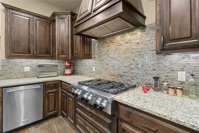 kitchen featuring stainless steel appliances, custom exhaust hood, dark brown cabinetry, and decorative backsplash