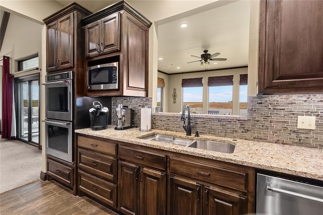 kitchen with sink, crown molding, dark brown cabinets, appliances with stainless steel finishes, and backsplash