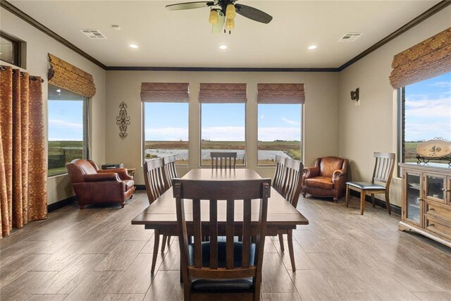 dining room featuring crown molding, a water view, wood-type flooring, and ceiling fan