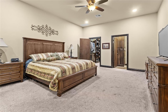 bedroom with a spacious closet, light carpet, and ceiling fan