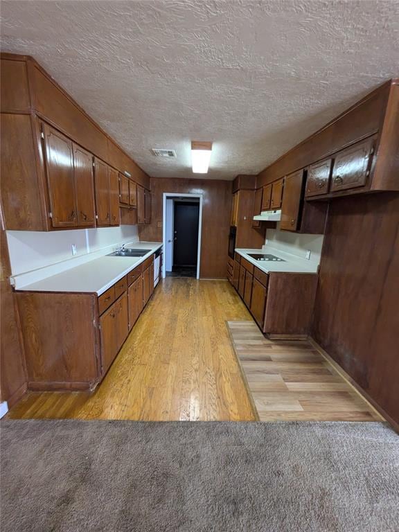 kitchen with sink, white stovetop, a textured ceiling, and light wood-type flooring