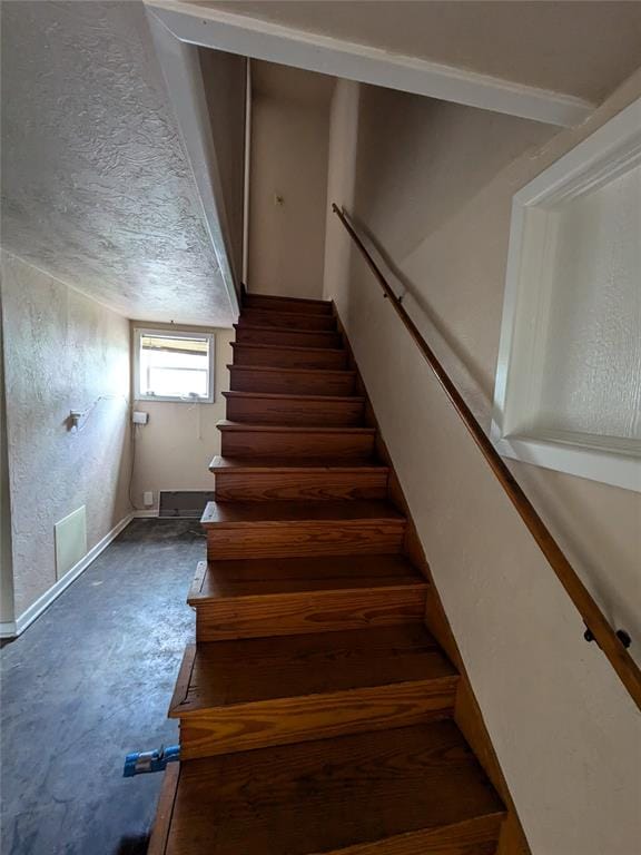 staircase featuring concrete floors and a textured ceiling