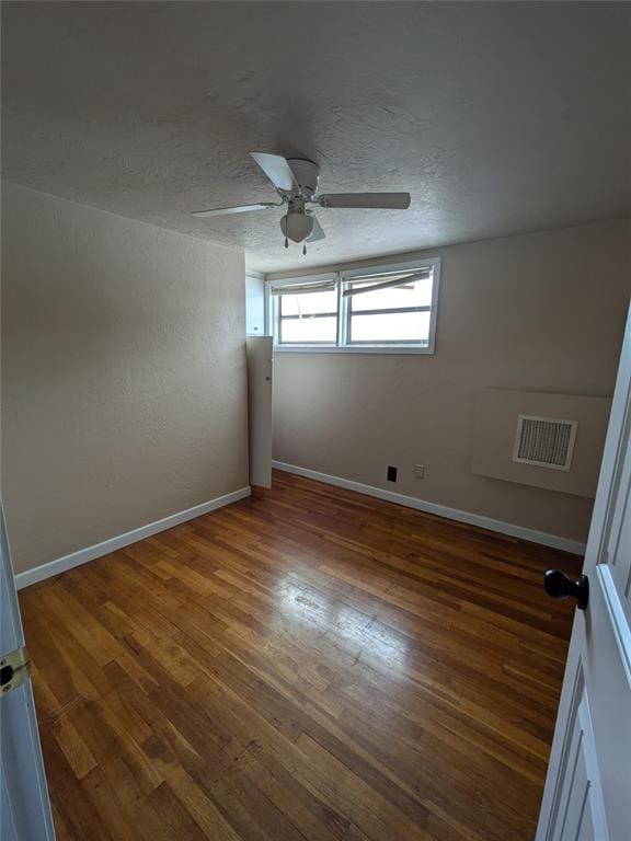 unfurnished room with a textured ceiling, dark hardwood / wood-style flooring, and ceiling fan