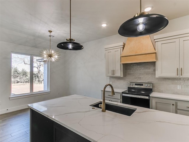 kitchen with light stone countertops, hanging light fixtures, stainless steel range with electric stovetop, and sink