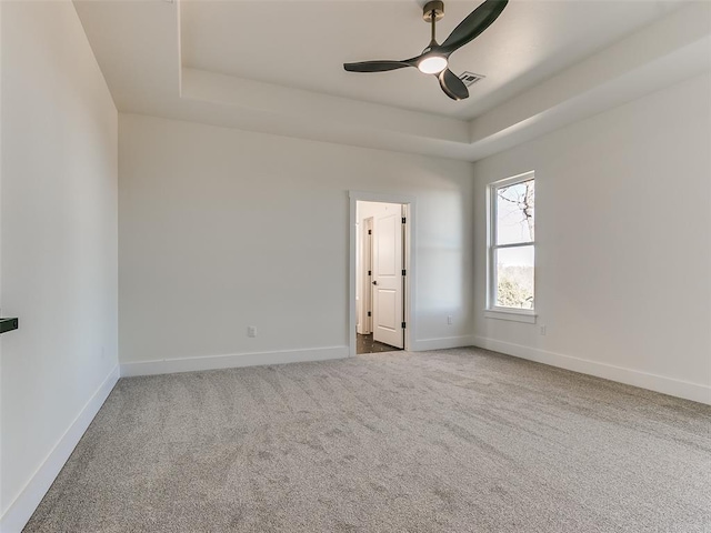 unfurnished room with a tray ceiling, ceiling fan, and carpet flooring