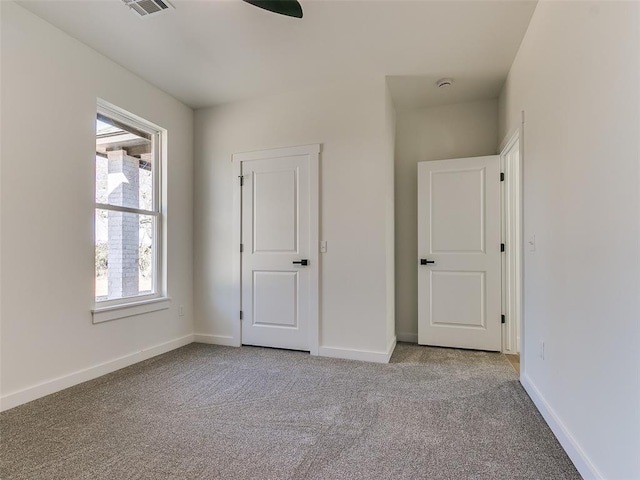 unfurnished bedroom with light carpet, multiple windows, and ceiling fan