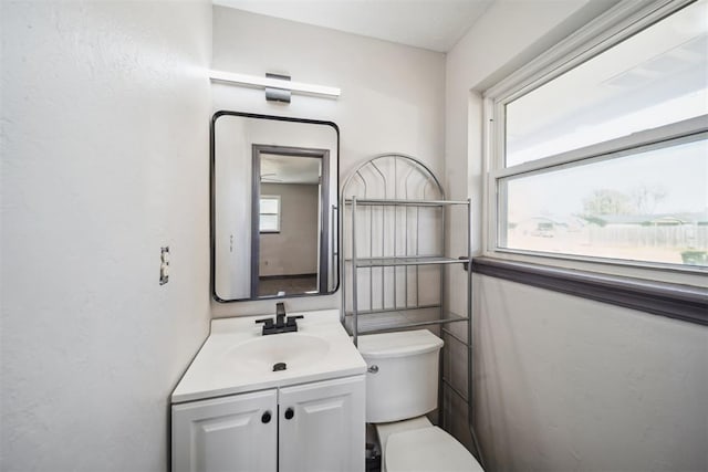 bathroom with a healthy amount of sunlight, vanity, and toilet