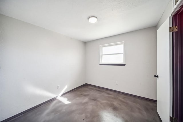 empty room featuring concrete flooring and baseboards