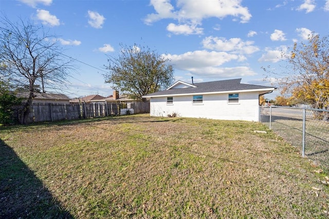 rear view of house with a lawn and a fenced backyard