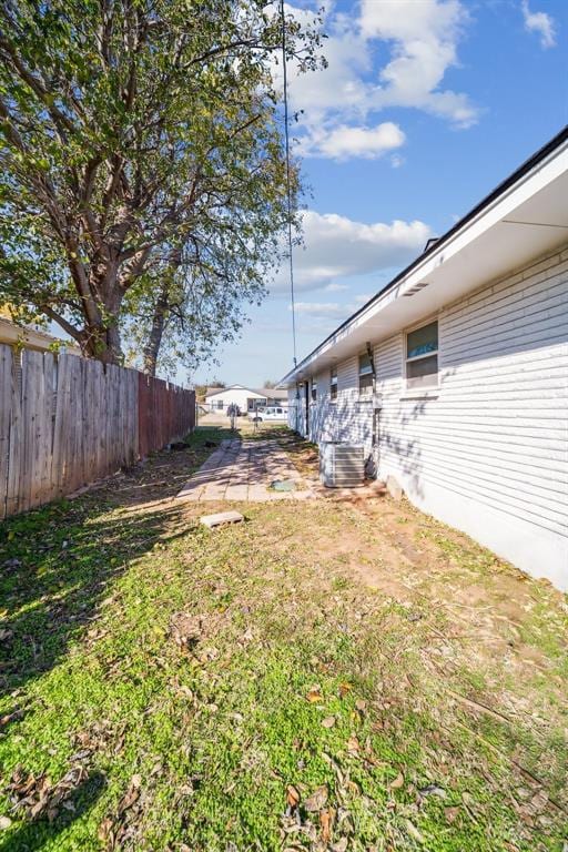 view of yard featuring central AC unit and fence