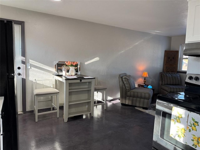 kitchen featuring concrete floors, under cabinet range hood, stainless steel electric range, and white cabinets