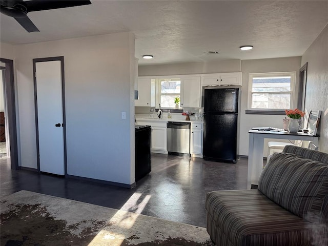 kitchen featuring light countertops, freestanding refrigerator, white cabinets, a sink, and dishwasher