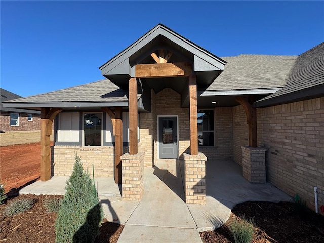 property entrance with brick siding and roof with shingles