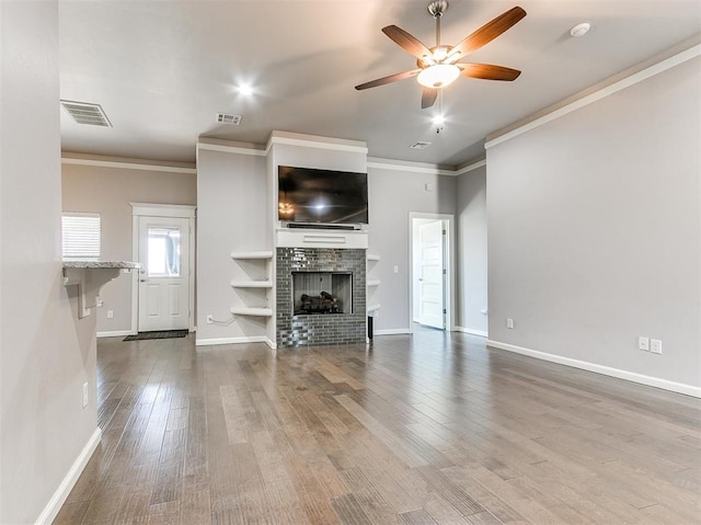 unfurnished living room with hardwood / wood-style flooring, a fireplace, ceiling fan, and crown molding