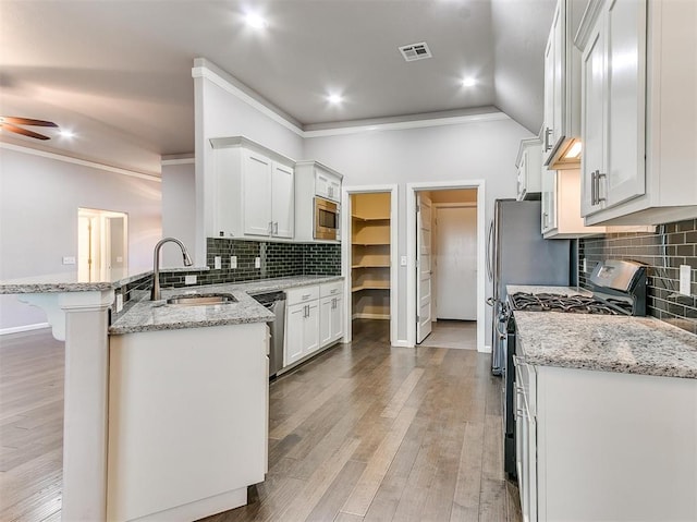 kitchen featuring white cabinetry, sink, stainless steel appliances, light stone counters, and light wood-type flooring