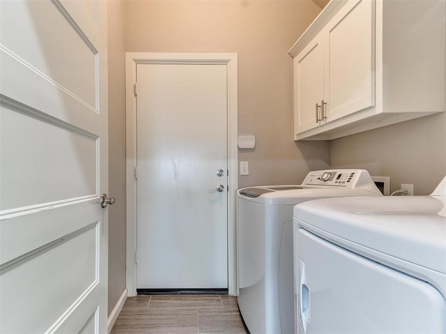 washroom with washing machine and dryer, light hardwood / wood-style flooring, and cabinets