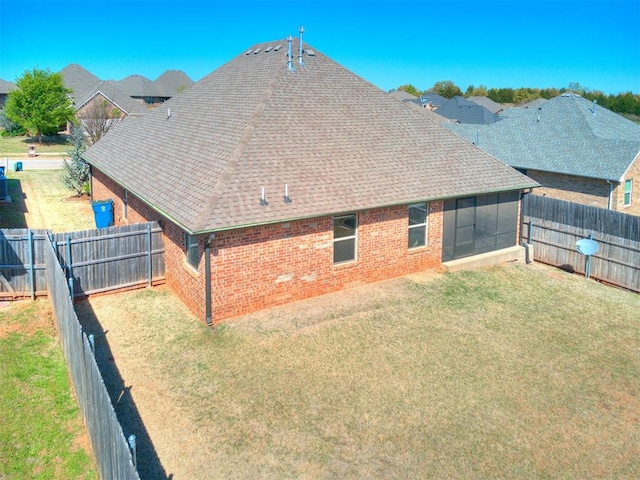 rear view of property with a sunroom and a yard