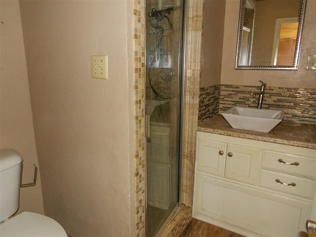 bathroom with vanity, wood-type flooring, decorative backsplash, toilet, and a shower with shower door