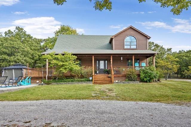 cabin with covered porch and a front yard