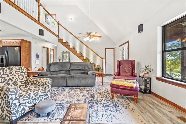 living room with light hardwood / wood-style floors, high vaulted ceiling, and ceiling fan