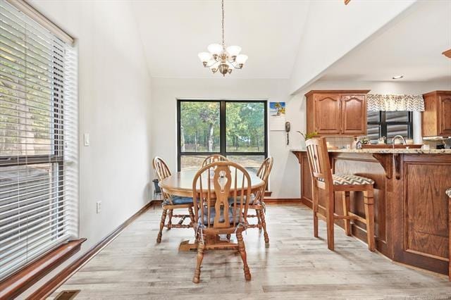 dining space with a notable chandelier, light wood-type flooring, and lofted ceiling