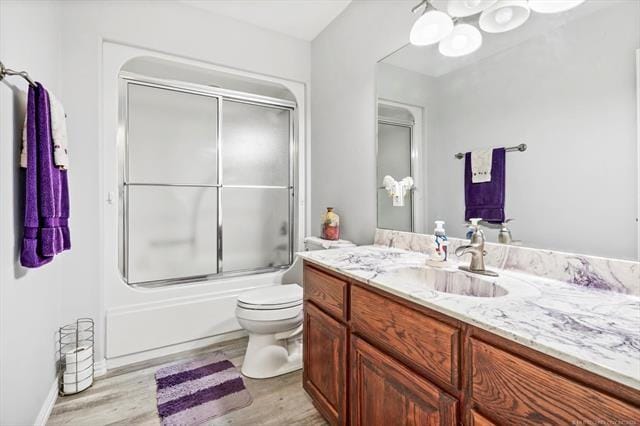 full bathroom with toilet, vanity, enclosed tub / shower combo, and hardwood / wood-style flooring