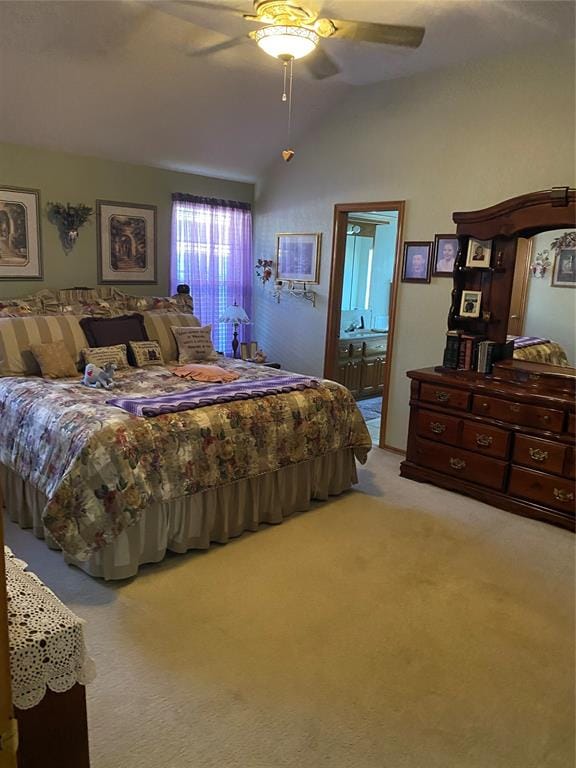 bedroom with ensuite bath, ceiling fan, light colored carpet, and vaulted ceiling