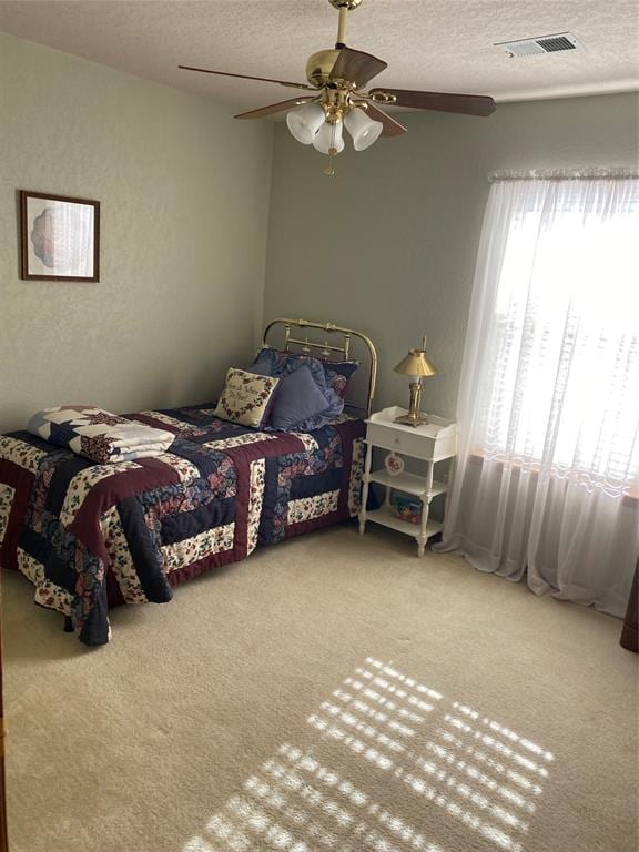 carpeted bedroom with ceiling fan and a textured ceiling