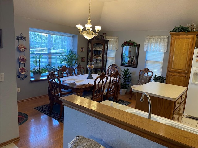 dining room with a chandelier, wood-type flooring, and lofted ceiling