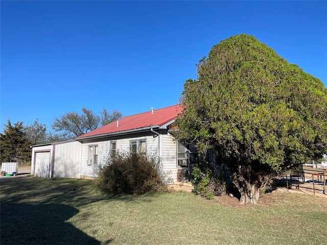 view of side of home featuring a garage, an outdoor structure, and a yard