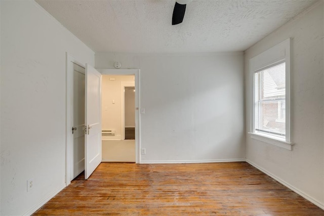 spare room with a textured ceiling, a baseboard radiator, and light hardwood / wood-style flooring