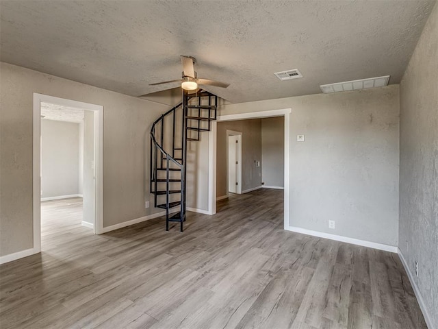 unfurnished living room with ceiling fan, light wood-type flooring, and a textured ceiling