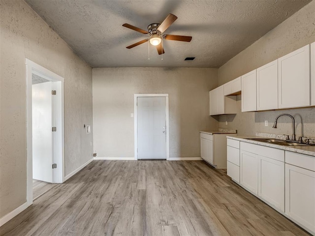 kitchen with ceiling fan, sink, white cabinets, and light hardwood / wood-style flooring