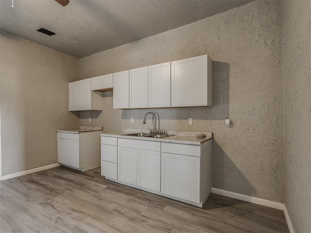 kitchen with white cabinets, sink, and light hardwood / wood-style flooring