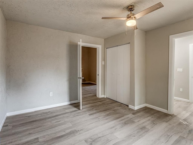 unfurnished bedroom featuring ceiling fan, light hardwood / wood-style floors, a textured ceiling, and a closet