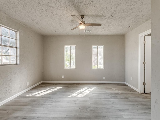 empty room with a textured ceiling, light hardwood / wood-style flooring, and ceiling fan